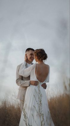 a bride and groom standing in tall grass