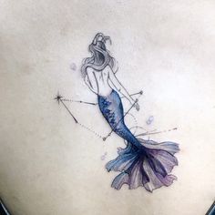 a woman's back with a blue mermaid tattoo on her left side and an arrow in the middle