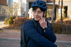 a man with a bicycle helmet on talking on his cell phone while standing in the street