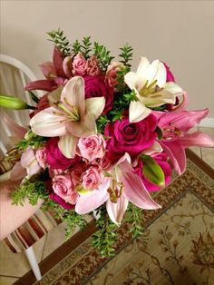 a bouquet of pink and white flowers sitting on top of a table next to a chair