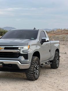 a silver truck is parked on the dirt