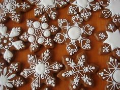 many decorated cookies on a wooden table with white icing and snowflakes