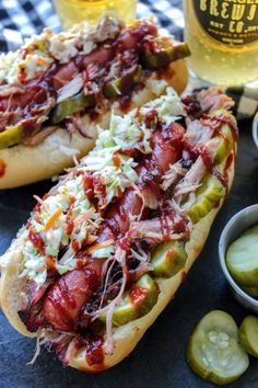 two hotdogs with pickles, cheese and ketchup on a table