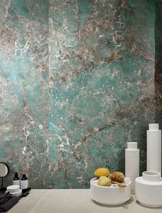 a bathroom with green marble walls and white pedestals in front of the tub area