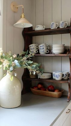 a vase filled with flowers sitting on top of a counter next to plates and cups