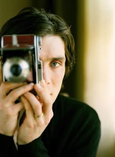 a man taking a selfie with an old camera in front of his face,