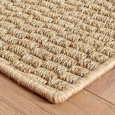 a close up view of a woven area rug on a wooden floor with wood floors