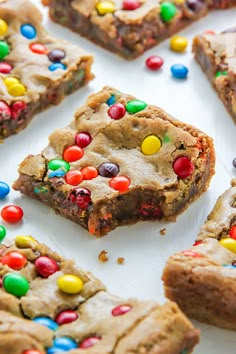 several pieces of cookie bars with m & m candy on top and one piece cut in half