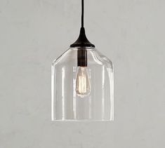 a clear glass pendant light hanging from a ceiling fixture with a black cord attached to it