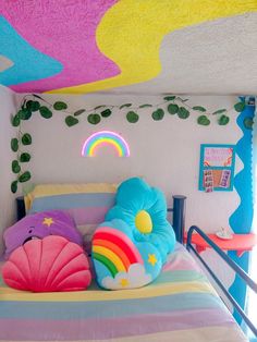 there is a bed with pillows on it and a rainbow painted ceiling above the bed