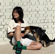 a woman sitting on the ground with her dog