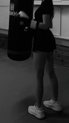 a woman standing in a gym with a punching bag