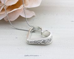 a heart shaped pendant on a chain next to a flower