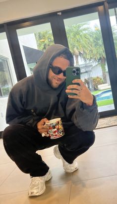 a man taking a selfie with his cell phone and coffee cup in front of him