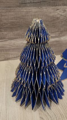 an origami christmas tree made out of blue paper on top of a wooden table