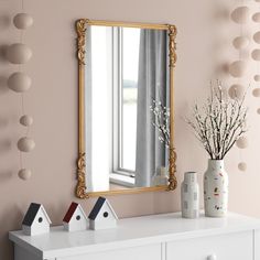 a white dresser topped with a mirror next to a vase filled with baby's breath flowers