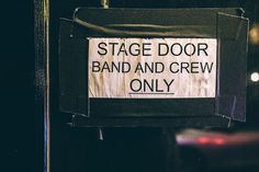 a sign that says stage door band and crew only hanging on the side of a building