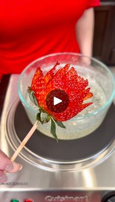 a person holding a flower in a glass bowl on top of a stove burner