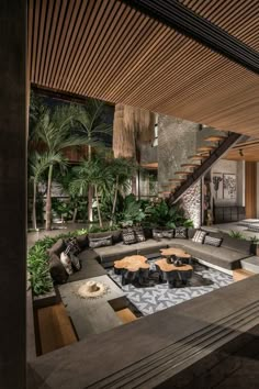 a living room filled with lots of furniture under a wooden ceiling above a fire pit