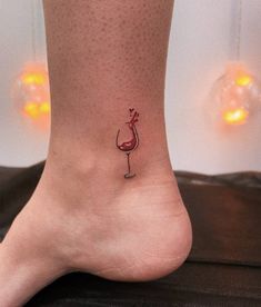 a woman's foot with a small wine glass tattoo on the bottom of it