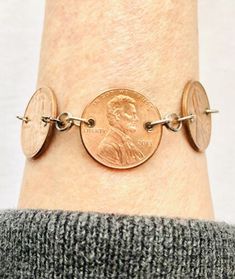 a person wearing a coin bracelet on their wrist