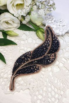 a black beaded brooch sitting on top of a white lace covered table cloth