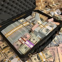 a suitcase filled with money sitting on top of a pile of cash