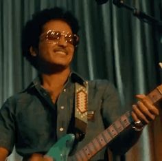 a man with sunglasses playing an electric guitar