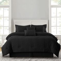 a bed with black comforter and pillows in a room