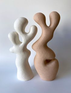 two white and beige vases sitting next to each other on a white table top