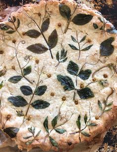 an uncooked pie with green leaves on it