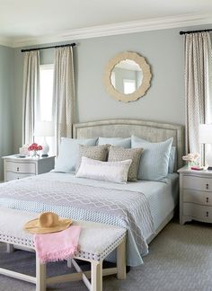 a bedroom with blue walls and white bedding in the corner, along with a hat on the footboard