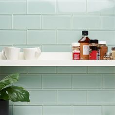 the shelf is filled with spices and condiments, along with two mugs