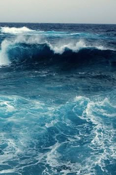 two surfers are riding the waves on their surfboards in the ocean with blue water