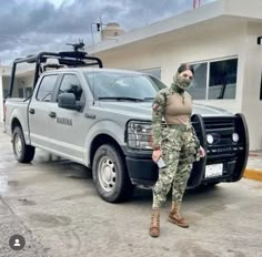 a woman in camouflage standing next to a truck