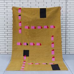 a yellow blanket with pink and black squares on it