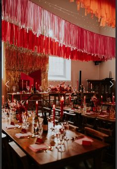 a dining room set up for a party with red and orange streamers