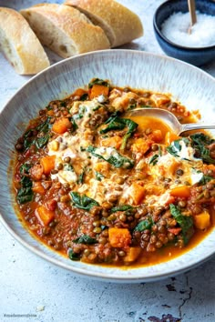 a white bowl filled with soup next to bread