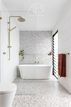 a white bath tub sitting next to a toilet in a bathroom