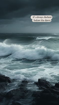 an ocean with waves crashing on the rocks and dark clouds in the sky above it