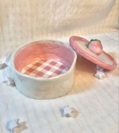 a pink bowl with a strawberry in it on a white tablecloth next to the bowl