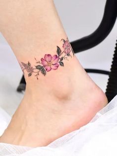 a woman's foot with a flower tattoo on the side of her ankle,