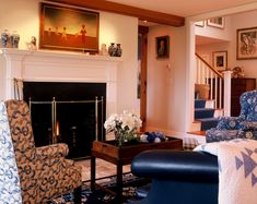 a living room filled with furniture and a fire place next to a stair case in front of a painting on the wall