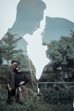 a man and woman standing next to each other in front of a giant photo with trees