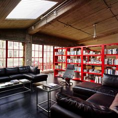 a living room filled with black furniture and lots of bookshelves next to large windows