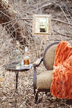 an old chair with a blanket on it in the woods