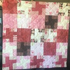 a pink and brown patchwork quilt hanging on a wall