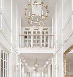 an elegant hallway with white walls and gold chandelier over the doorway, leading to another room