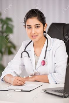 a female doctor sitting at her desk in front of a laptop computer with a stethoscope on it