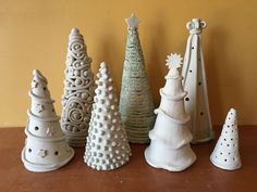 a group of ceramic christmas trees sitting on top of a wooden table